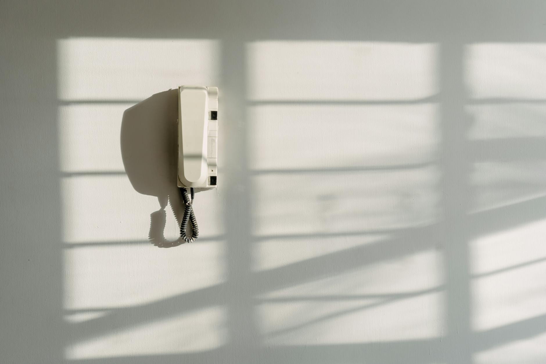 white entry phone on a white wall with shadow cast from a window