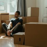 man in blue crew neck t shirt sitting on brown cardboard box