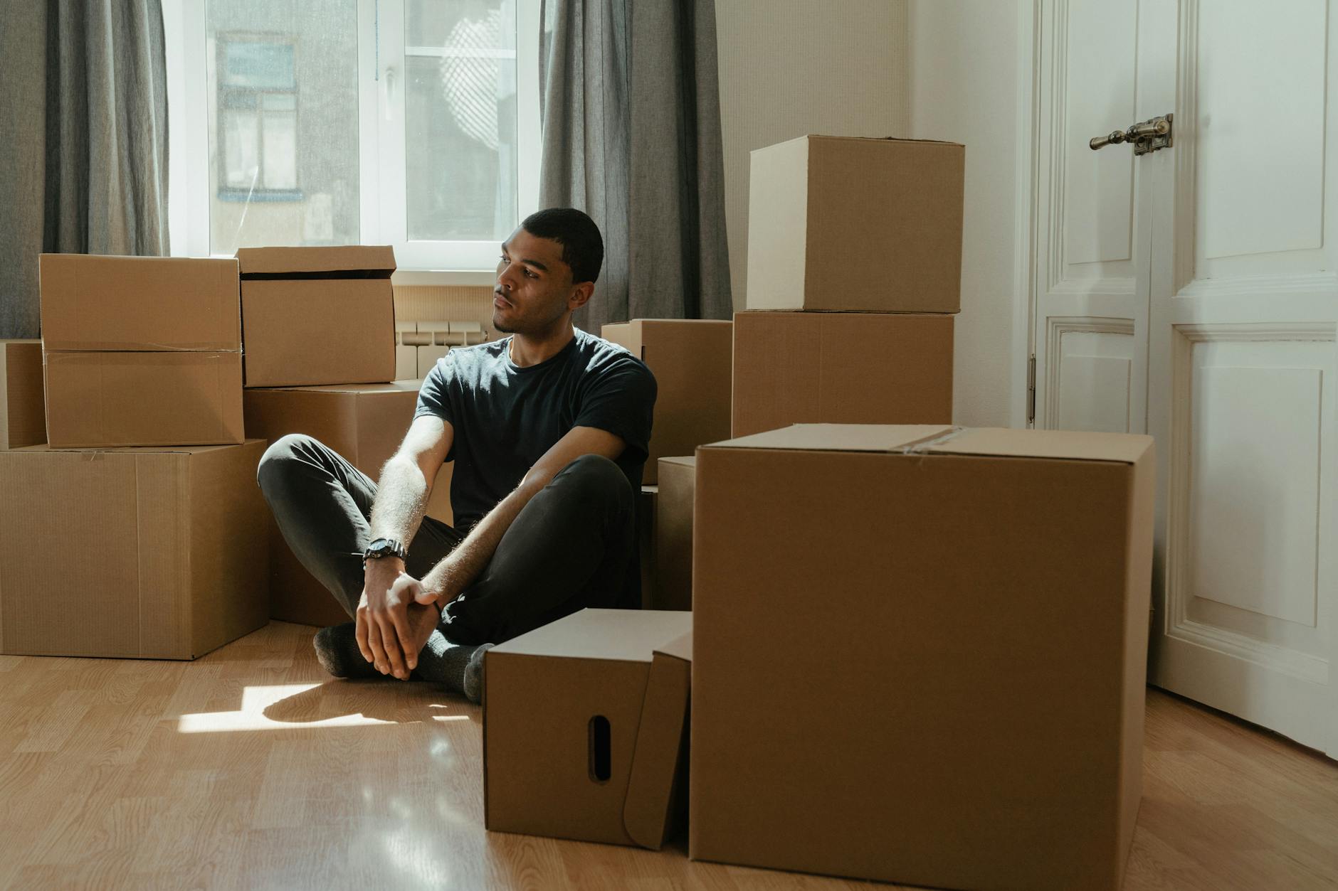 man in blue crew neck t shirt sitting on brown cardboard box