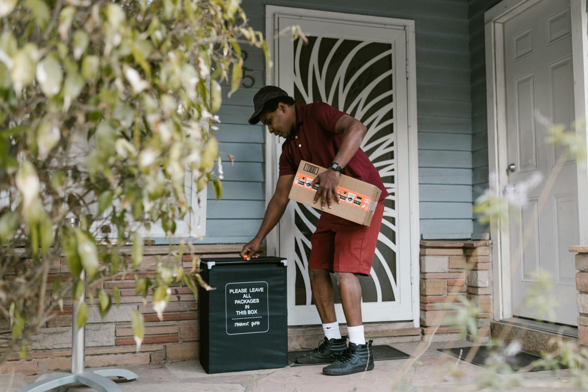 delivery courier placing parcel in box on porch