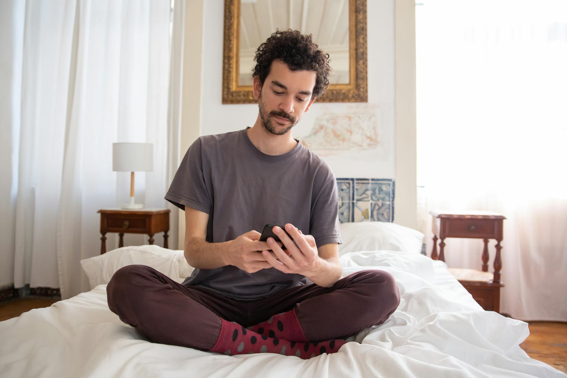 a man looking at his smartphone on the bed