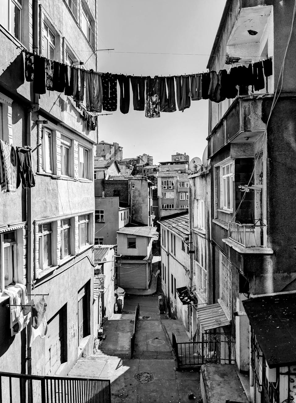 a black and white photo of a street with clothes hanging on the line
