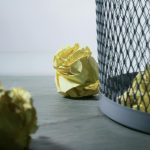focus photo of yellow paper near trash can
