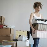 concentrated woman carrying stack of cardboard boxes for relocation